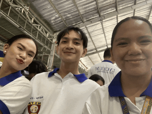 a man and two women pose for a picture with a man wearing a shirt that says muxcrm on it