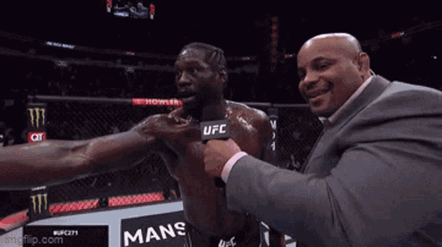 a man in a suit is interviewing a fighter in a ufc cage