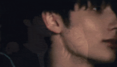 a close up of a man 's face in a dark room with a blurry background .
