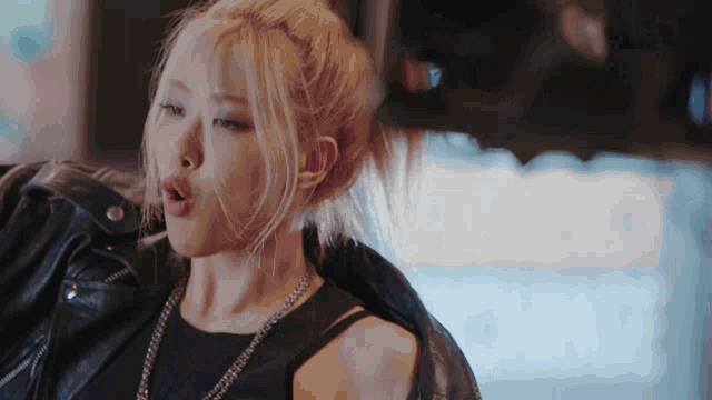 a woman with blonde hair is wearing a black leather jacket