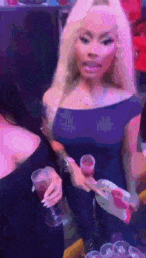 a woman in a black dress is holding a shot glass