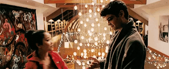 a man and a woman are standing next to each other in a living room in front of a christmas tree .