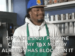 a man wearing an apron and a blue hat is standing in a kitchen talking about tax money .