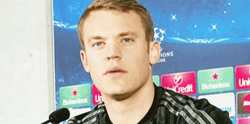 a man is standing in front of a microphone in front of a sign that says champions league .