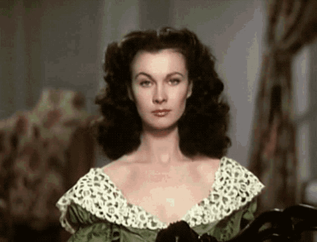 a woman in a green dress with a white lace collar is looking at the camera