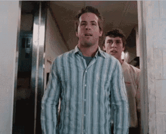 a man in a striped shirt is standing in a hallway with two other men behind him .