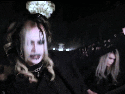 a woman with a crown on her head is standing in a dark room .