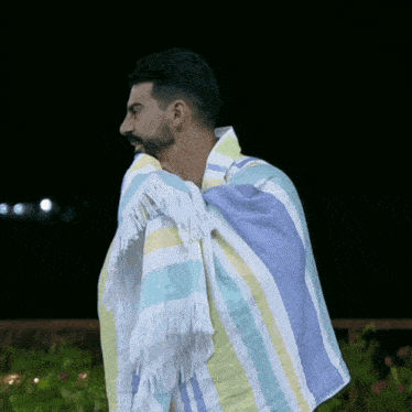 a man wrapped in a colorful striped towel with fringe