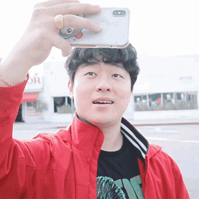 a man in a red jacket takes a selfie with an iphone