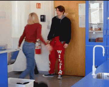 a man wearing red pants with the word wilzim on them holds hands with a woman