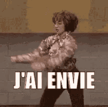 a woman is dancing in front of a brick wall and the words `` j'ai envie '' are written on the screen .