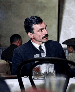 a man in a suit and tie sits at a table