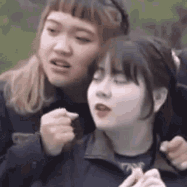 a couple of girls are sitting next to each other and one of them is eating a piece of chocolate .