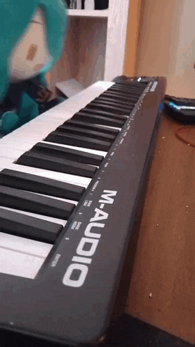a black m-audio keyboard is sitting on a wooden table