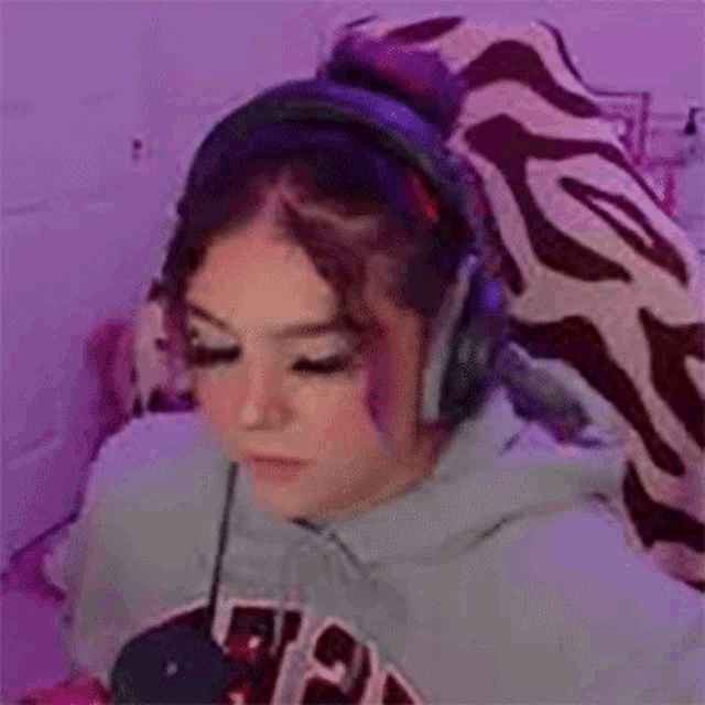 a girl is wearing headphones and making a funny face while sitting on a bed .