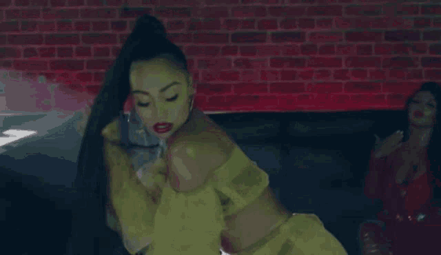 a woman in a yellow dress is laying on a couch next to another woman