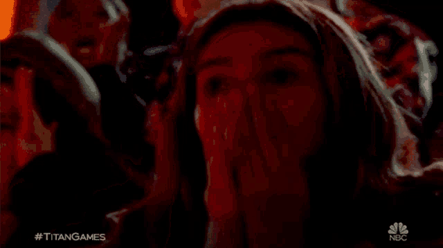 a woman covering her face in a crowd with the nbc logo visible