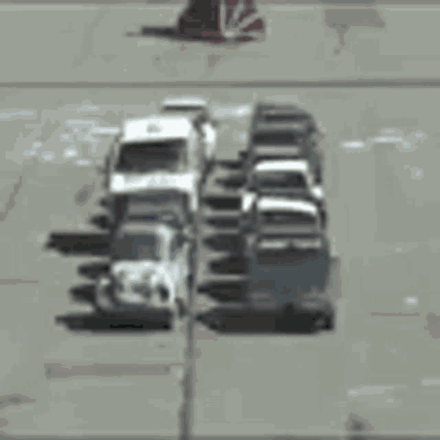 a row of trucks are driving down a street next to a red cone .