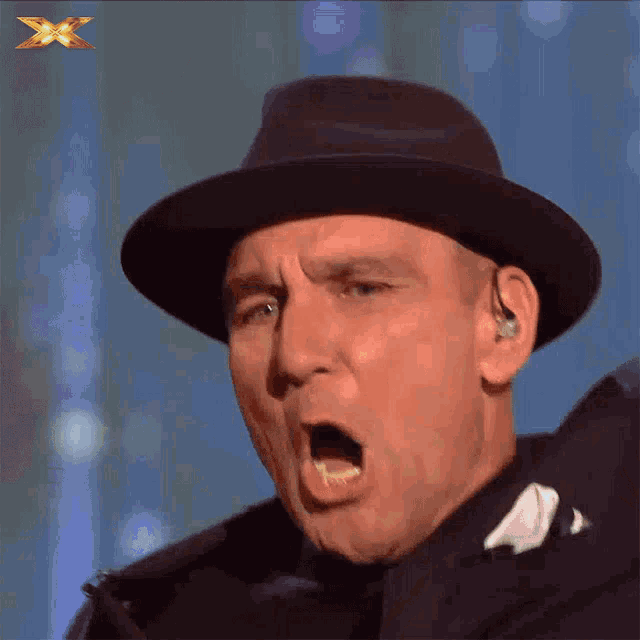 a man wearing a fedora is making a funny face with an x on the bottom right