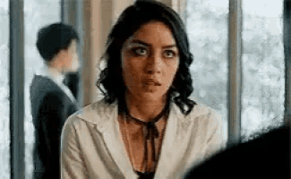 a woman in a white shirt and tie is looking at the camera .