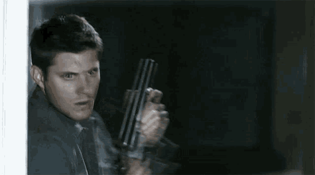 a man in a grey shirt is holding a knife in his right hand .