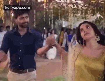 a man and a woman are holding hands and dancing in a crowded area .