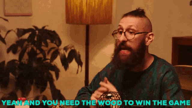 a man with a beard and glasses says " yeah and you need the wood to win the game " while sitting at a table