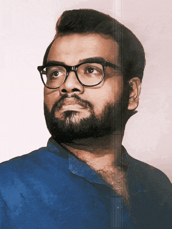 a man with glasses and a beard looks to his left