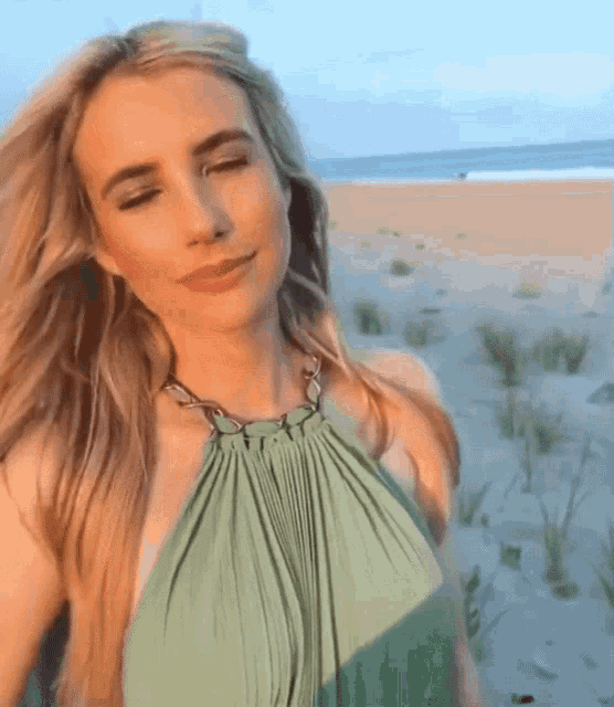 a woman in a green top is standing on a beach