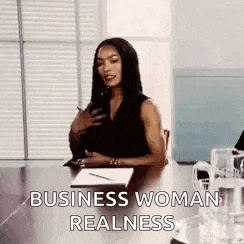 a woman is sitting at a conference table holding a cell phone and a notebook .