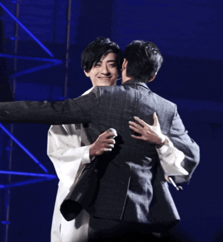 two men hugging each other in front of a blue background