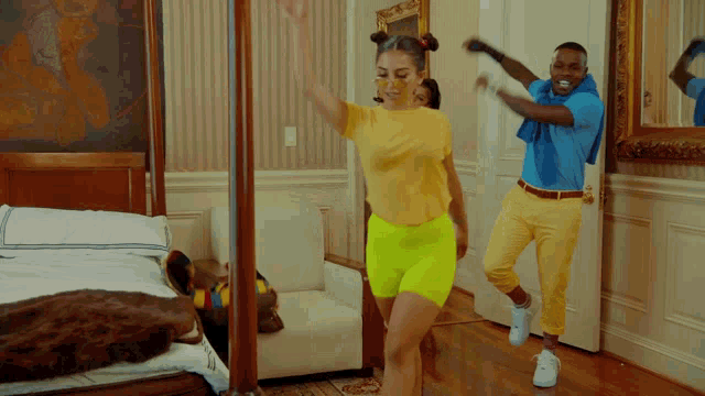 a man and woman are dancing in a bedroom with a cat on the bed