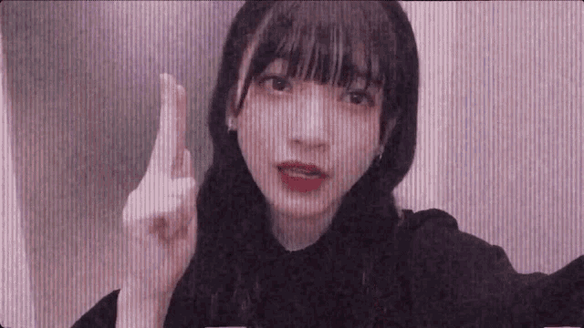 a young girl is making a funny face and pointing her finger at the camera .