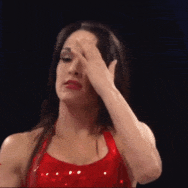 a woman in a red dress is covering her eyes with her hand .