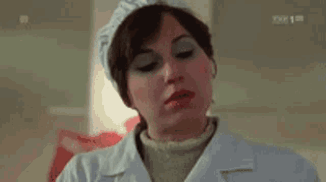 a woman wearing a chef 's hat and a white coat is making a funny face .