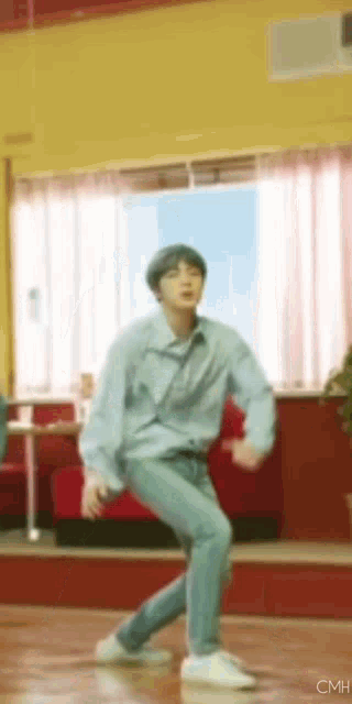a man in a blue shirt and jeans is dancing in a room .