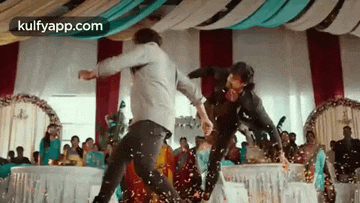 two men are fighting in a room with a crowd of people watching .