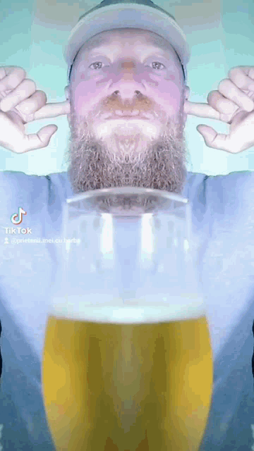 a man with a beard is covering his ears with his hands while holding a glass of beer