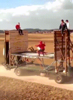 a man in a red shirt sits on top of a wooden structure