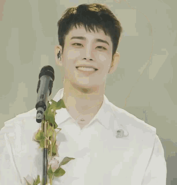 a man in a white shirt stands in front of a microphone