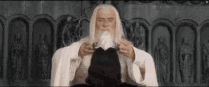 a man with long white hair and a beard is sitting in front of a wall holding a sword .