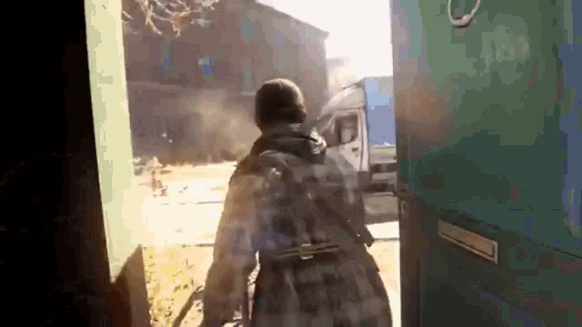 a man with a backpack is walking through a doorway with a truck in the background .