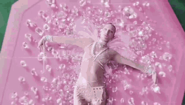 a woman is laying on top of a pink umbrella covered in diamonds .