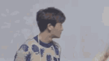 a young man in a blue and white sweater is waving at the camera .