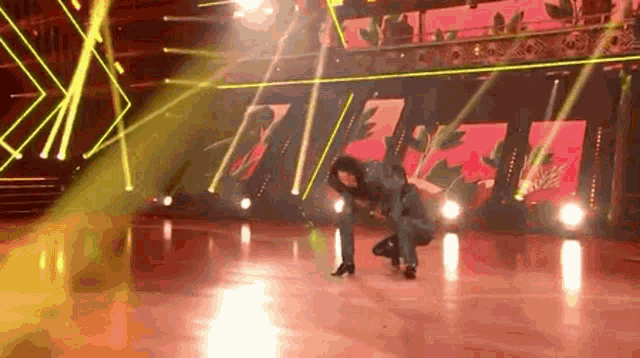 a woman is kneeling down on a dance floor in front of a stage .