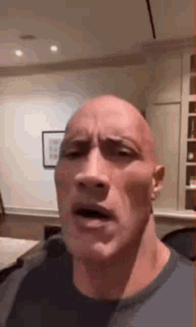 the rock is making a funny face with his mouth open in a living room .