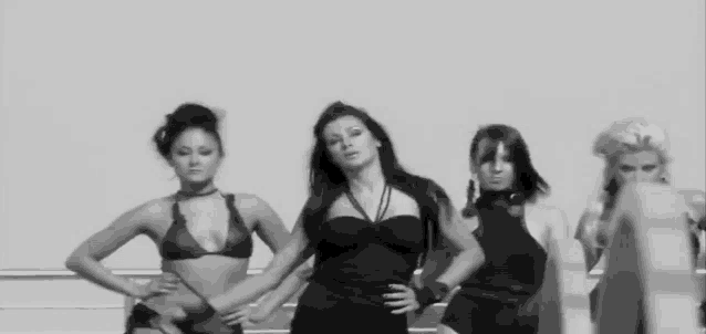 a black and white photo of four women in bikinis dancing