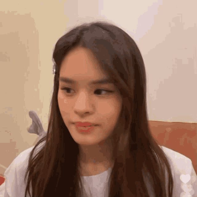 a woman with long hair is sitting on a couch and making a funny face .
