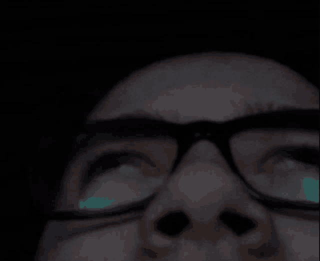 a close up of a person wearing glasses looking up