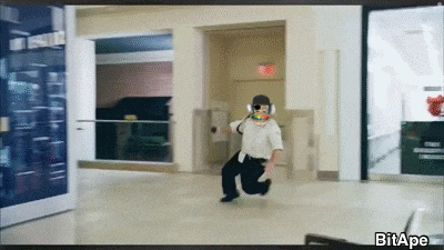a man in a white shirt and black pants is running in a hallway with a sign that says exit on it